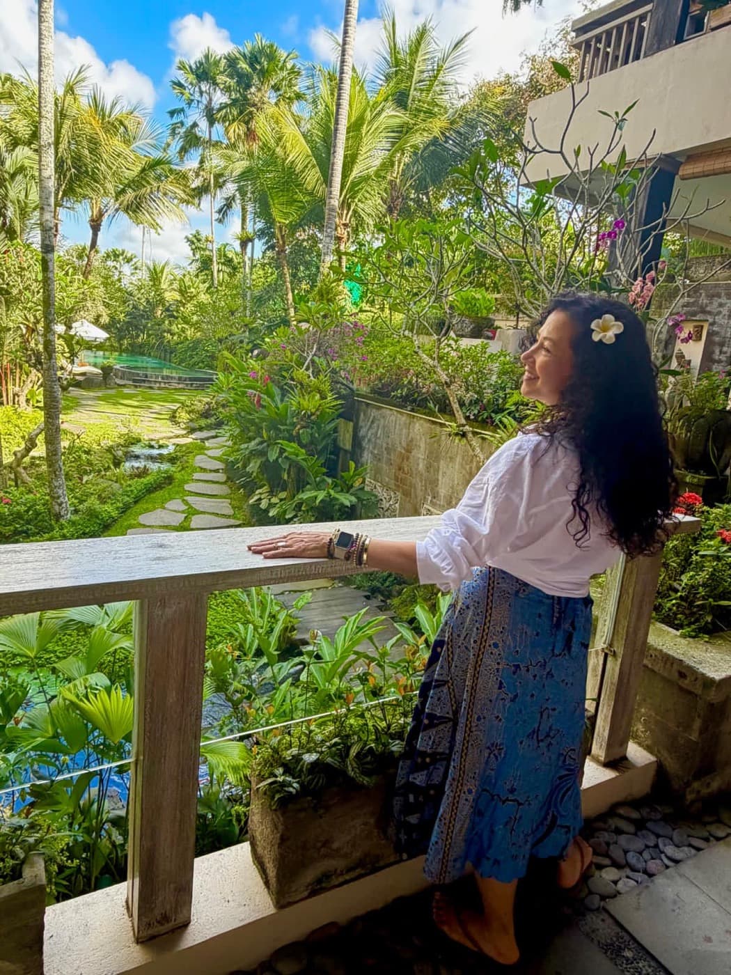 Cynthia haciendo una pausa en un balcón entre plantas, mirando hacia el jardín