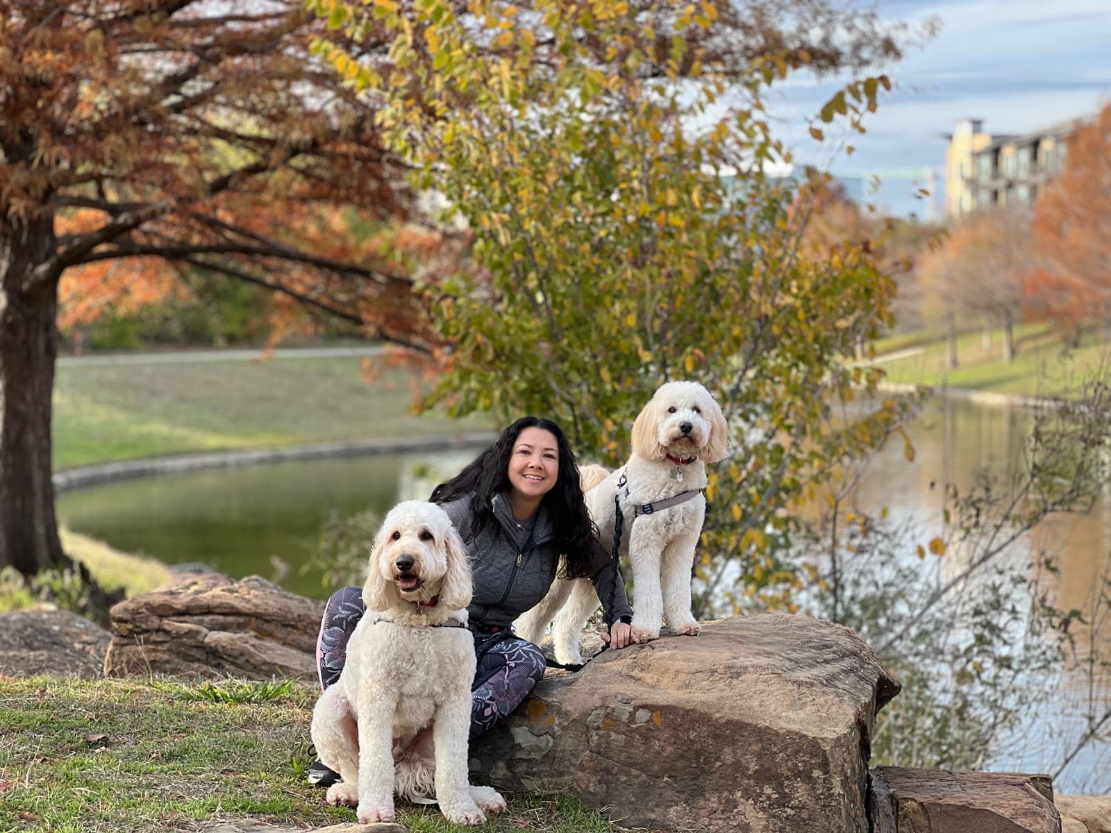 Cynthia al aire libre junto a sus dos perros cerca de un estanque